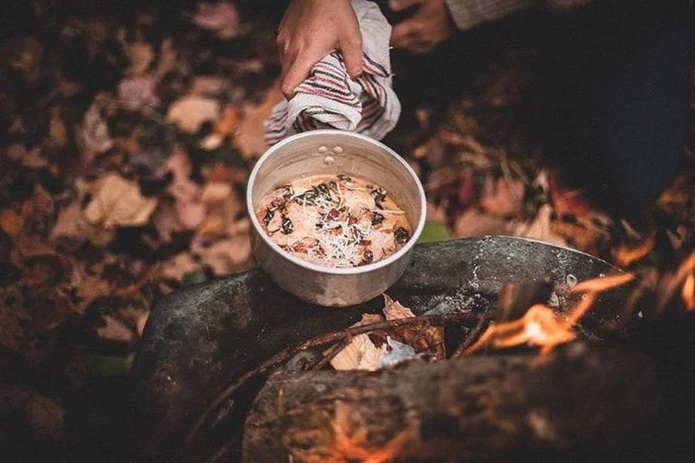 Casserole posée sur un feu de bois, feuilles d’automne au sol