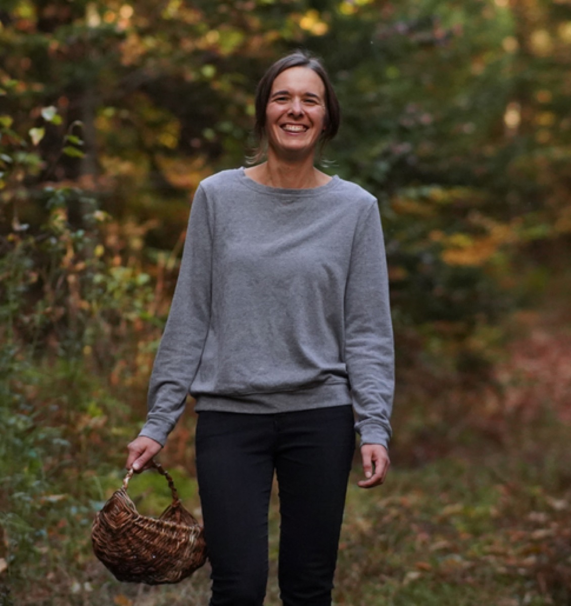 Joanie Bélanger, souriante, panier à la main dans la forêt